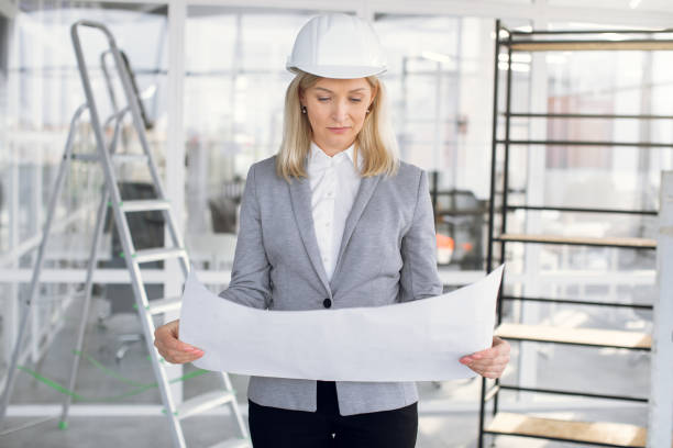 istock Successful business lady in helmet working with blueprint 1305465096