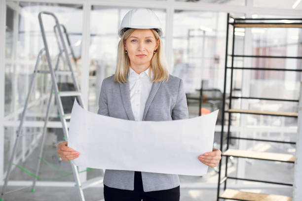 istock Woman in hardhat working with drawings on construction 1305465106