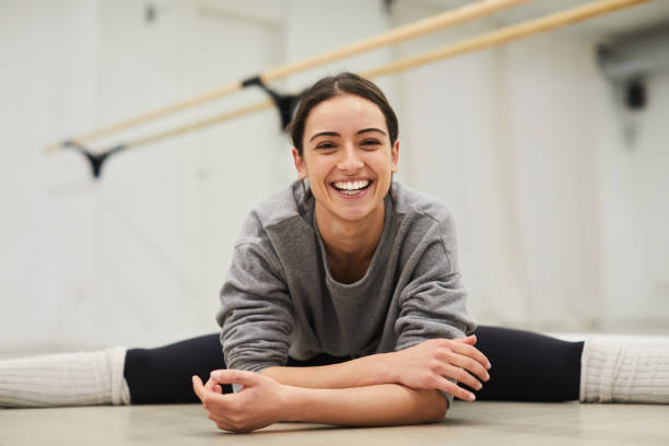 porträt des yogalehrers, der die splits macht und in die kamera lächelt. - the splits ethnic women exercising stock-fotos und bilder