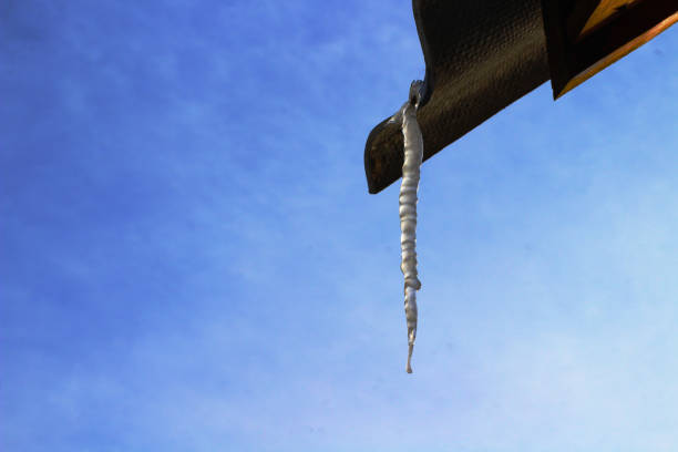 istock Crystal Icicle against Blue Cloudy Sky Hanging from Roof n Spring 1305472516