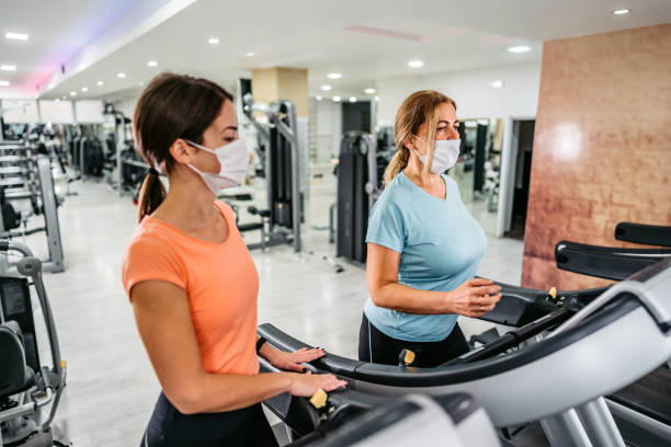 istock Senior woman running on treadmill with trainers help 1305474097