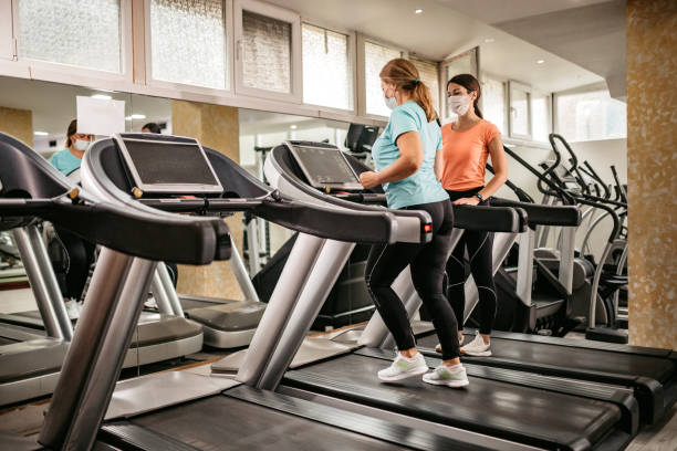 istock Senior woman running on treadmill with trainers help 1305474148