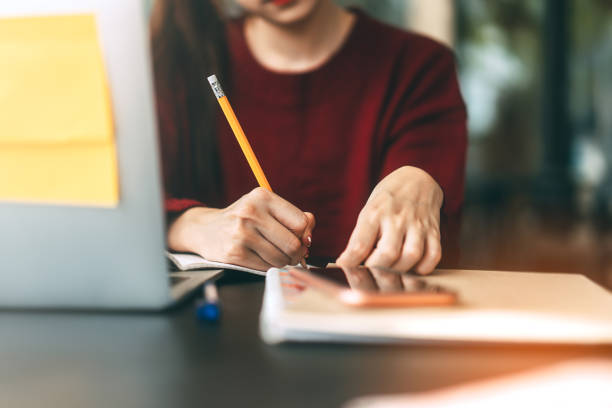 istock Closeup hand young adult women writing note for study and work online at cafe. 1305474476