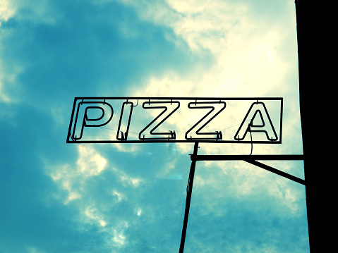 Pizza sign silhouette over cloudy blue sky