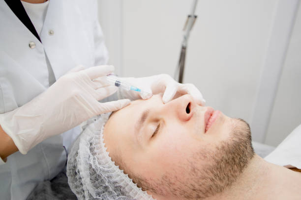 istock Cosmetologist's making injections to man's face to remove scars and wrinkles and make it smooth 1305476987