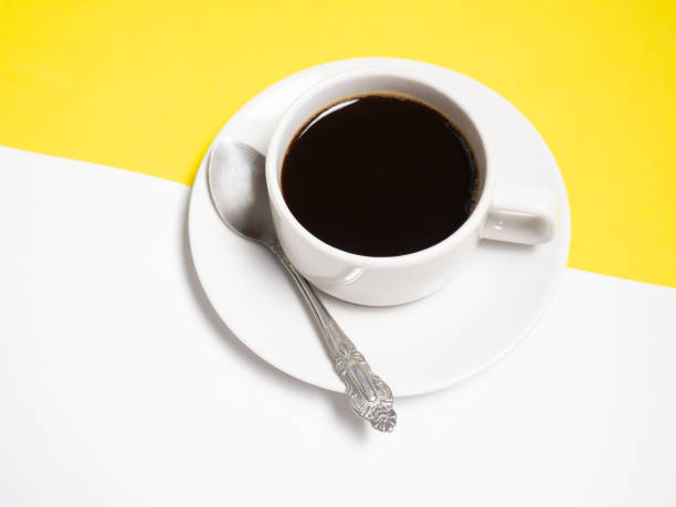 istock Black coffee in a white cup on a yellow background, copy space 1305477516