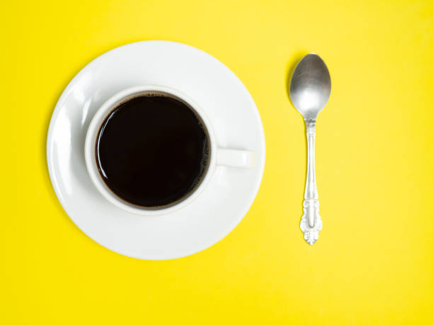 istock Black coffee in a white cup on a yellow background, copy space 1305477521
