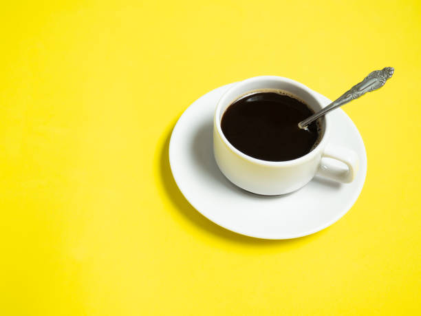 istock Black coffee in a white cup on a yellow background, copy space 1305477522