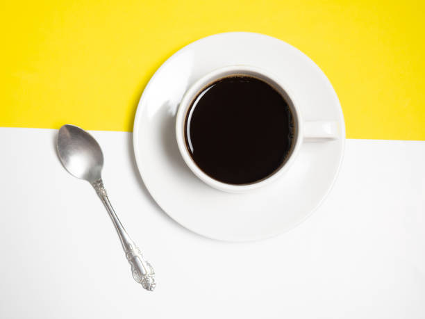 istock Black coffee in a white cup on a yellow background, copy space 1305477523