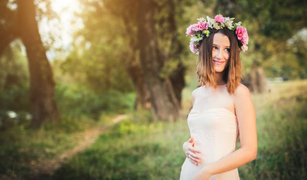 Young brunette beauty with floral wreath on her head in nature.