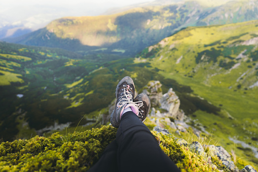 View of a woman's hiking boots lying with the scenic view of the beautiful mountains during summer  sunset