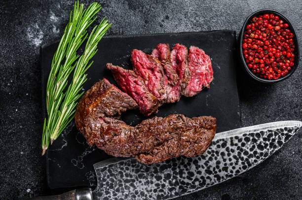 istock Sliced grilled Onglet Hanging Tender steak on a marble board. Black background. Top view 1305479548