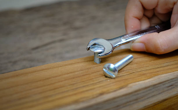 close-up de uma mão de marceneiro com uma porca de chave de fenda um parafuso de móvel em uma prancha de madeira - screw human head bolt isolated - fotografias e filmes do acervo