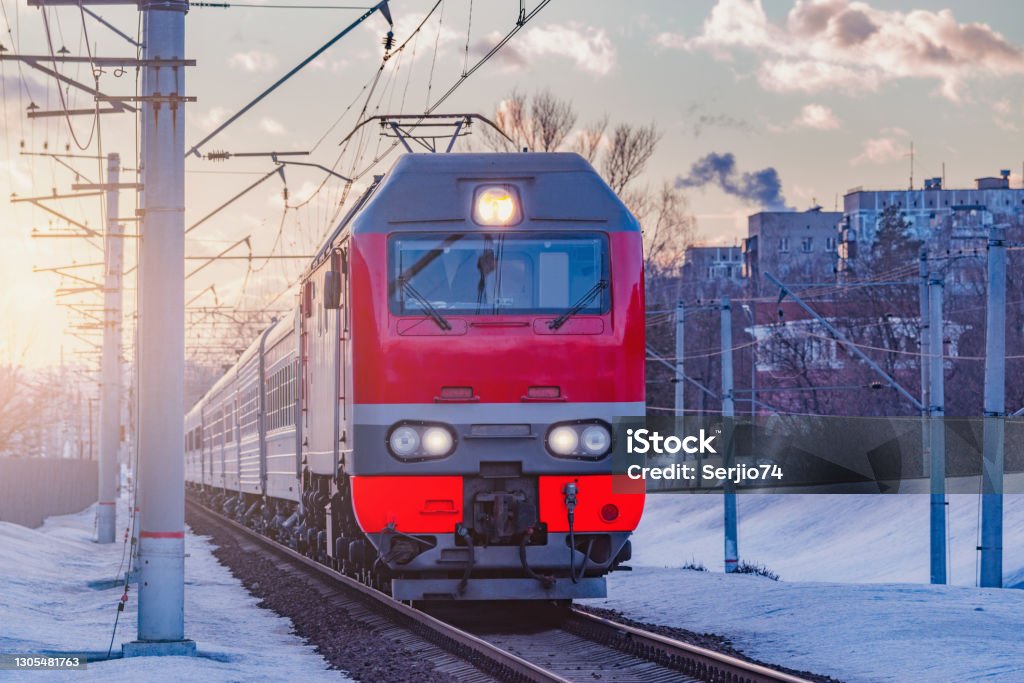 Passenger train moves from the station. Passenger train moves from the station at sunset winter. Train - Vehicle Stock Photo