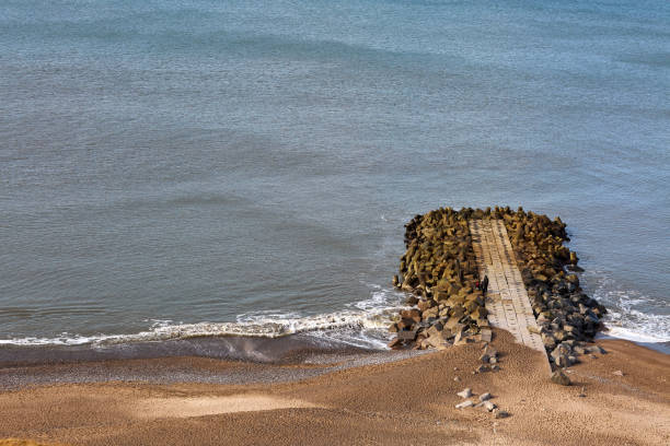 pequeno caminho de rocha saindo para a água na praia - tide going out - fotografias e filmes do acervo
