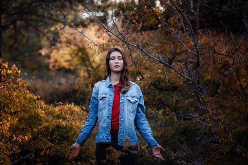 Girl travels in the mountains forest. A girl in a denim jacket and red T-shirt. Mountains in autumn. Travel Lifestyle and survival concept