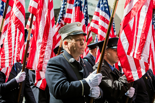 New York, USA - March 17, 2016:  Firemen with flags at the St. Patrick's Day Parade along 5th Avenue.