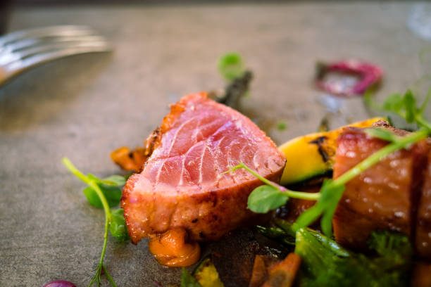 Detail of a medium roasted tuna steak served with microgreens Detail of a medium roasted tuna steak served with microgreens and grilled vegetables, fine food, seafood serving fusion food stock pictures, royalty-free photos & images