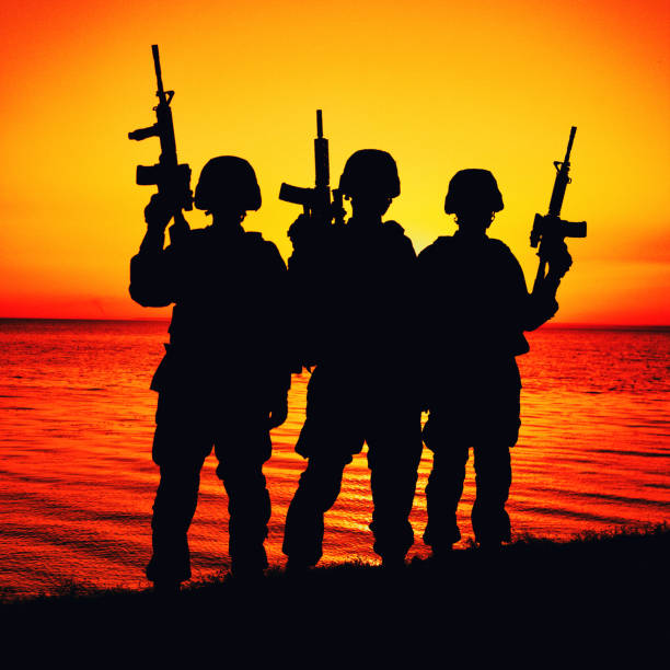 istock Army soldiers team standing on seashore at sunset 1305492568