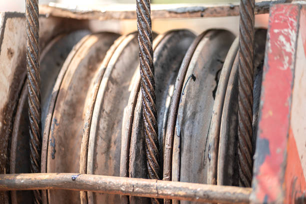 Wire rope sling and crawler drum of the lifting crane machine. Close-up and selective focus at sling's part. Industrial object equipment photo.