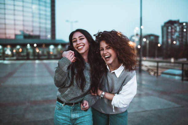 istock Smiling Female Beauties Embracing While Walking Together Outside 1305496503