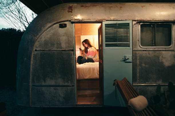 istock Young woman with smart phone inside a motor home 1305496681