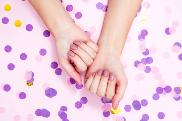 istock Elegant nude manicure on a pink background with confetti 1305498298
