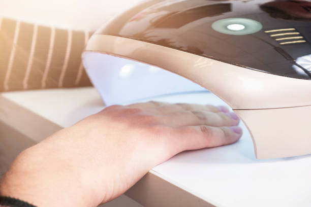 istock Female hand in an ultraviolet lamp during a manicure procedure 1305499008