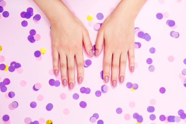 istock Elegant nude manicure on a pink background with confetti 1305499072