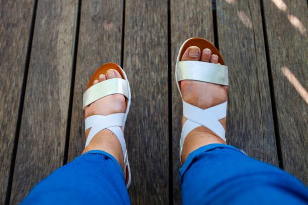 istock Female feet in white sandals 1305499129