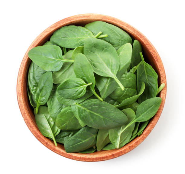 istock Spinach leaves in a wooden plate on a white. Top view. 1305500607