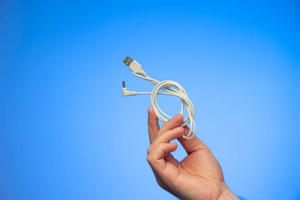 istock White folded USB charging cable held in hand by Caucasian male hand studio shot isolated on blue background 1305500690