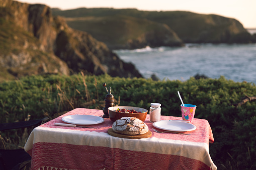 Picture of a decorated table on the cliffs of spain for dinner. In the background you can sea the Atlantic ocean.