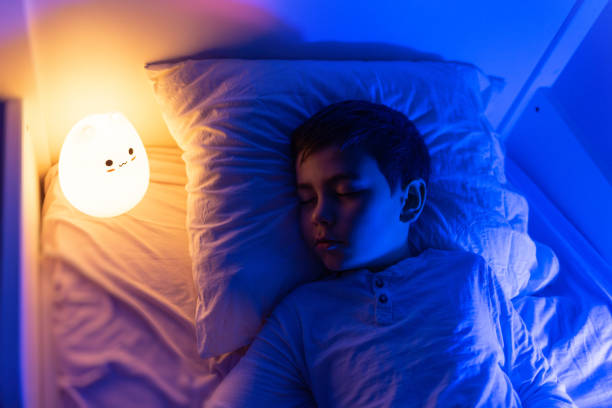 6 years old boy sleeping with led night lamp, soft focus six years old bouy sleep with LED night lamp, School child dreaming. Kid angry of darkness. baby sleeping bedding bed stock pictures, royalty-free photos & images