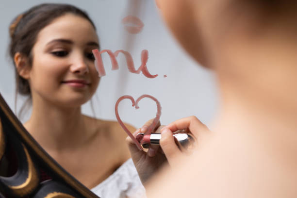 foto borrada de uma jovem posando em frente a um espelho. coração com batom no espelho. - mirror women kissing human face - fotografias e filmes do acervo