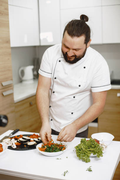 istock Handsome man cooking at home preparing salad in kitchen 1305508617
