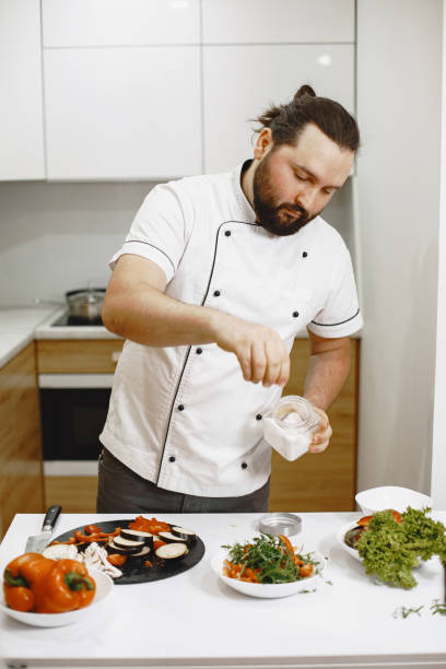 istock Handsome man cooking at home preparing salad in kitchen 1305508645