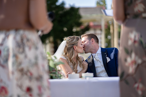 wedding couple beautiful bride and handsome bridegroom kissing oiutdoors on sunny summer day during wedding ceremony