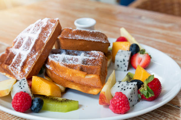 istock Belgian waffles with fresh fruit and caramel on white plate on wooden table. 1305510116