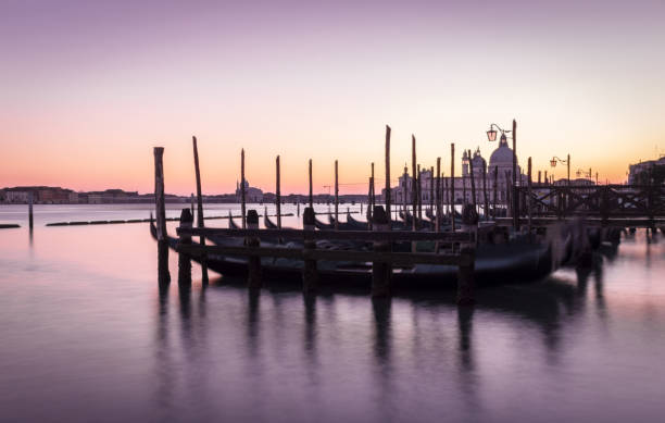 vista en venecia y góndolas con puesta de sol púrpura - venice italy ancient architecture creativity fotografías e imágenes de stock