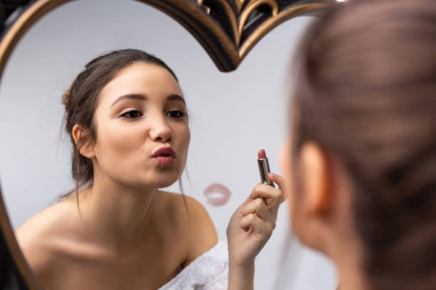 home make-up. morgenkuss im spiegel. kaukasische mädchen malt ihre lippen mit roten lippenstift. reflexion im spiegel. vergrößertes foto. - mirror women kissing human face stock-fotos und bilder