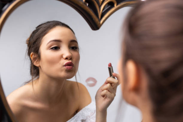 makijaż domowy. poranny pocałunek w lustrze. kaukaska dziewczyna maluje usta czerwoną szminką. odbicie w lustrze. powiększone zdjęcie. - mirror women kissing human face zdjęcia i obrazy z banku zdjęć