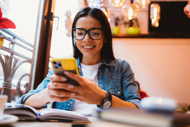 istock Happy young woman student holding smart phone 1305512748