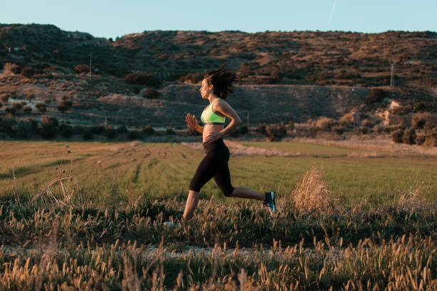 istock Woman runner running through the spring meadow. Workout in a nature. 1305512881