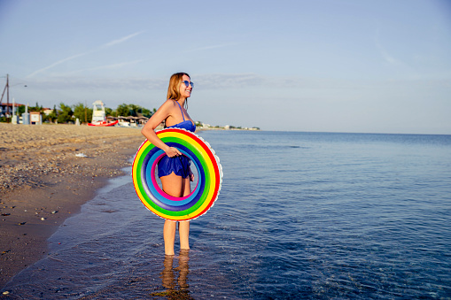 Young smiling woman with inflatable ring on the beach
