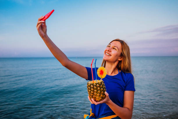 istock Woman with pineapple cocktail taking selfie 1305513818