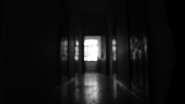 Blurred silhouette of an unknown man walking in the dark corridor.