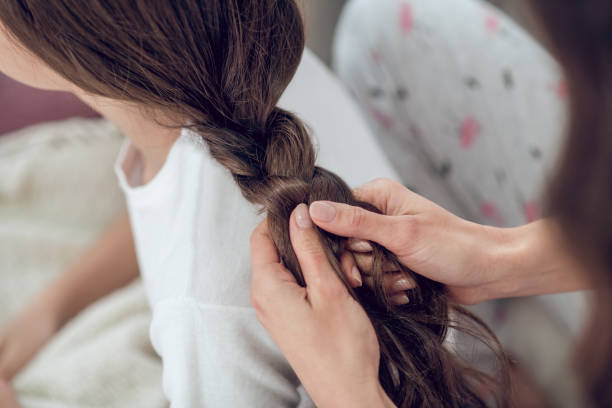 istock Female hands braiding long dark hair in braid 1305513968
