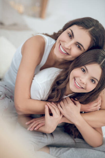 Caring mother hugging joyful daughter tightly