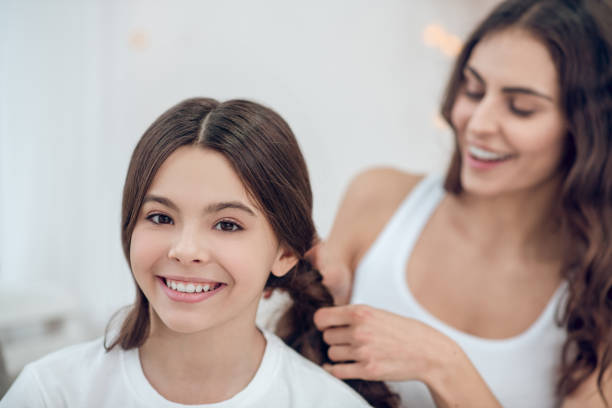 istock Mom braiding her happy daughters braids 1305514196